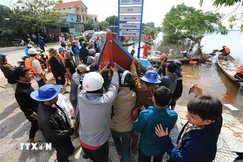  Các ngư dân chuyển thuyền đi biển xuống vùng lũ tại huyện Lệ Thủy hỗ trợ công tác cứu trợ đồng bào. (Ảnh: Thành Đạt/TTXVN)