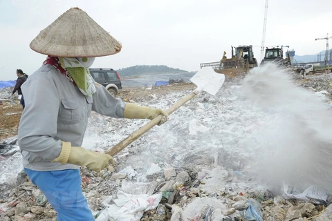 Công nhân Công ty TNHH MTV Môi trường Đô thị Hà Nội rắc chế phẩm khử mùi tại bãi rác Nam Sơn. (Ảnh: Mạnh Khánh/TTXVN)