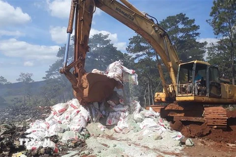 Lực lượng chức năng huyện Bảo Lâm dùng xe cơ giới phá hủy các bao phân bón trước khi chôn lấp để tiêu hủy hoàn toàn. (Ảnh: TTXVN phát)