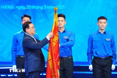 Ông Vương Đình Huệ - Ủy viên Bộ Chính trị, Bí thư Thành uỷ Hà Nội gắn Huân chương Lao động hạng Nhất lên cờ truyền thống của Thành đoàn Hà Nội. (Ảnh: Minh Đức/TTXVN)