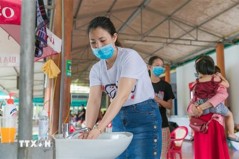 Du khách được hướng dẫn rửa tay sát khuẩn, đeo khẩu trang khi đến các điểm dịch vụ tại thị xã Cửa Lò. (Ảnh: Bích Huệ/TTXVN)