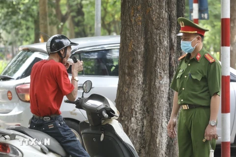 Lực lượng chức năng nhắc nhở, xử lý các trường hợp không đeo khẩu trang nơi công cộng. (Ảnh: Minh Quyết/TTXVN)