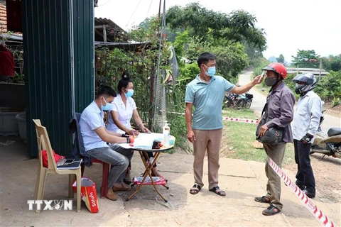 Lực lượng chức năng kiểm tra thân nhiệt đối với người dân đi qua khu vực bản Nà Bó, xã Nà Bó, huyện Mai Sơn. (Ảnh: Hữu Quyết/TTXVN)
