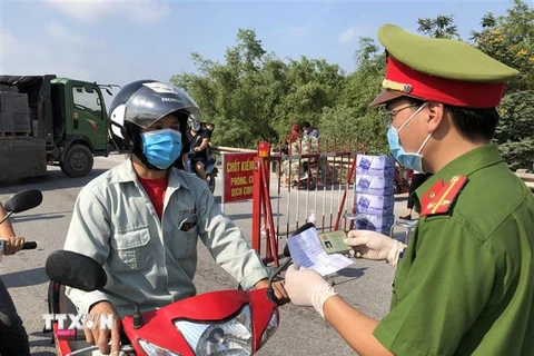 Lực lượng công an tại chốt kiểm dịch cầu Hồ, huyện Thuận Thành kiểm tra giấy tờ của người dân. (Ảnh minh họa: Đinh Văn Nhiều/TTXVN)