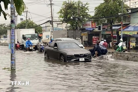 Nước ngập gần nửa bánh xe ôtô trên đường Phan Văn Hớn (quận 12). (Ảnh: Mạnh Linh/TTXVN)