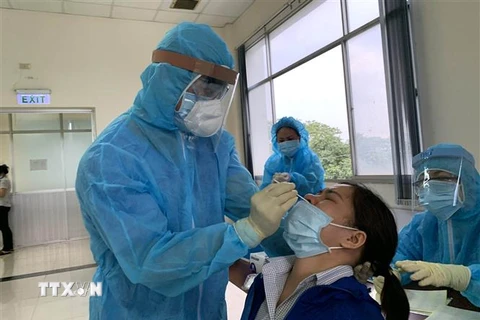 Các y, bác sỹ Trung tâm kiểm soát bệnh tật Thành phố Hồ Chí Minh và quận 7 thực hiện xét nghiệm sàng lọc COVID-19 ngẫu nhiên cho công nhân ngày 3/6. (Ảnh: Thanh Vũ/TTXVN)