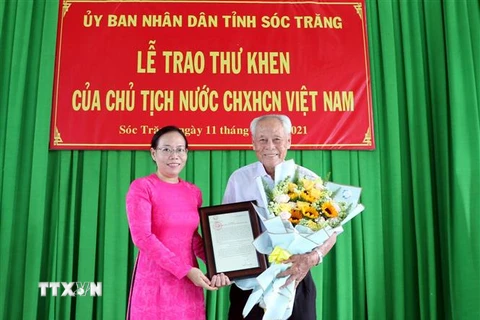 Phó Chủ tịch Ủy ban Nhân dân tỉnh Sóc Trăng Huỳnh Thị Diễm Ngọc trao thư khen của Chủ tịch nước cho cụ Trần Cang. (Ảnh: Trung Hiếu/TTXVN)