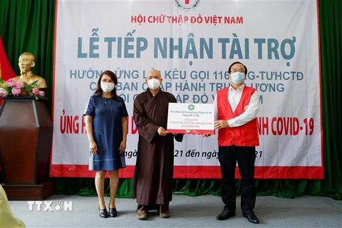 Thượng tọa Thích Thanh Phong trao bảng tượng trưng thiết bị y tế, kinh phí ủng hộ hỗ trợ tuyến đầu chống dịch. (Ảnh: TTXVN phát)