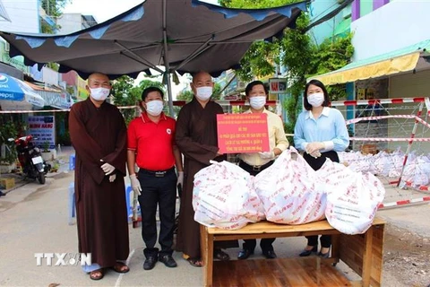 Ban Trị sự Giáo hội Phật giáo Việt Nam Quận 8 tặng quà cho các gia đình trong khu vực cách ly tại phường 4. (Ảnh: TTXVN phát)
