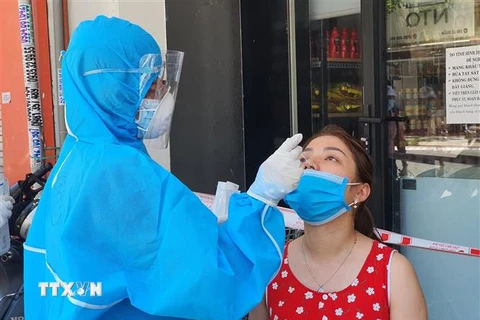 Nhân viên y tế lấy mẫu xét nghiệm của người dân quanh khu vực có ca mắc COVID-19 tại đường Lê Duẩn. (Ảnh: Văn Dũng/TTXVN)