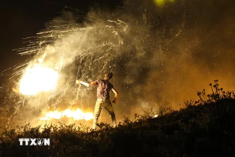 Người biểu tình Palestine ném chất cháy về phía binh sĩ Israel tại khu vực biên giới Gaza và Israel, ngày 15/6/2021. (Ảnh: AFP/TTXVN)