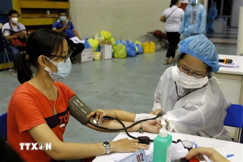 Lực lượng y bác sỹ thực hiện khám sàng lọc trước khi vào quy trình tiêm vaccine phòng COVID-19 tại Nhà thi đấu Phú Thọ. (Ảnh: Thanh Vũ/TTXVN)