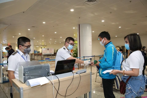 Nhân viên y tế kiểm tra phiếu khai báo y tế của hành khách. (Ảnh minh họa. Nguồn: TTXVN)