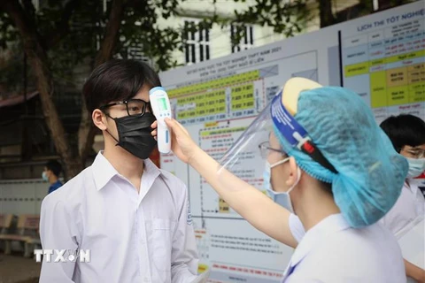 Kiểm tra thân nhiệt các thí sinh dự thi tại điểm thi Trường Trung học phổ thông Ngô Sỹ Liên, Bắc Giang. (Ảnh: Danh Lam/TTXVN)