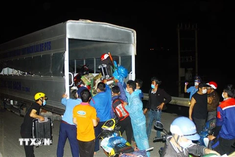 Lực lượng chức năng hỗ trợ đưa xe máy và hành lý của công dân Nghệ An từ các tỉnh phía Nam lên xe trung chuyển. (Ảnh: Tá Chuyên/TTXVN)