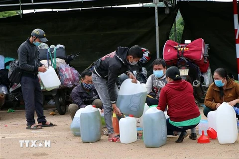 Người dân đi xe máy từ các tỉnh phía Nam về quê được lực lượng Cảnh sát giao thông Công an tỉnh Kon Tum hỗ trợ cơm, đồ ăn nhẹ, ước uống và xăng trước khi về quê ngày 27/7. (Ảnh: Cao Nguyên/TTXVN)