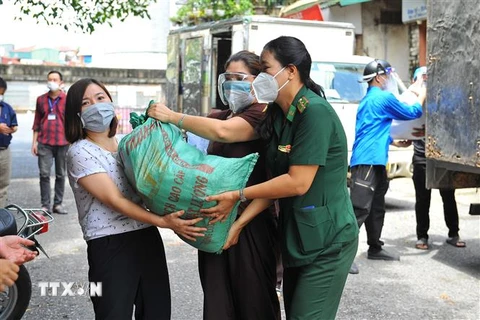 Lực lượng tình nguyện vận chuyển nhu yếu phẩm cho nhân dân phường Chương Dương và Phúc Tân. (Ảnh: Minh Đức/TTXVN)