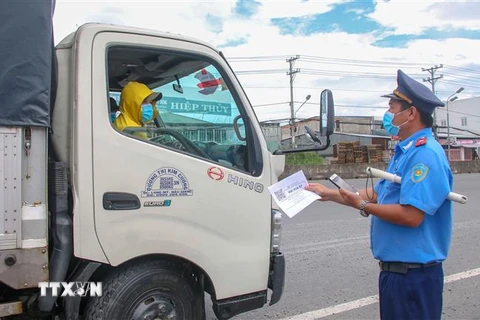 Lực lượng Thanh tra giao thông kiểm tra giấy tờ của một xe tải chờ hàng hóa vào thành phố Cần Thơ. (Ảnh: Thanh Liêm/TTXVN)