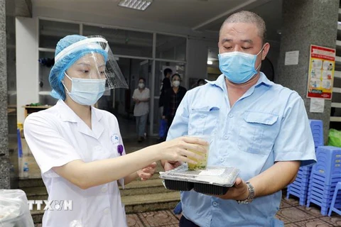  Đại diện lực lượng tuyến đầu chống dịch quận Hai Bà Trưng, Hà Nội đón nhận bữa trưa từ nhà hảo tâm. (Ảnh: Trần Việt/TTXVN)