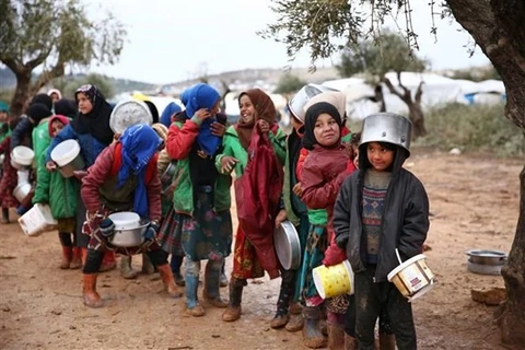 Trẻ em xếp hàng nhận thực phẩm cứu trợ tại một trại tị nạn ở tỉnh Aleppo, Syria. (Ảnh: AFP/TTXVN)