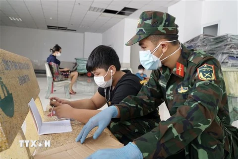 Cán bộ, chiến sỹ hỗ trợ các em học trực tuyến tại lớp học dã chiến ở chung cư 1050 (quận Bình Thạnh). (Ảnh: Thu Hương/TTXVN)