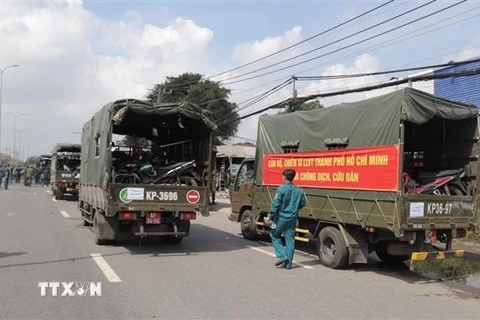 Lực lượng kiểm soát quân sự vận chuyển xe máy cho người dân lên xe ôtô chở về quê. (Ảnh: TTXVN phát)