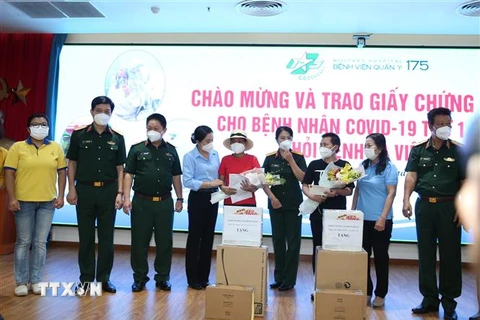Lãnh đạo Tổng cục Hậu cần và Bệnh viện Quân y 175 trao giấy chứng nhận ra viện và tặng hoa chúc mừng hai bệnh nhân. (Ảnh: Hồng Pha/TTXVN phát)