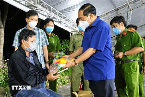 Thiếu tướng Nguyễn Văn Thuận, Giám đốc Công an thành phố Cần Thơ tặng quà hỗ trợ cho người dân về quê tại chốt kiểm soát ở quận Cái Răng tối 9/10. (Ảnh: Thanh Liêm/TTXVN)
