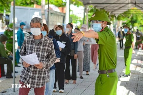 Hướng dẫn người tiêm thực hiện nghiêm việc phòng, chống dịch COVID-19 tại điểm tiêm Trung tâm Văn hóa quận Sơn Trà, Đà Nẵng. (Ảnh: Văn Dũng/TTXVN)