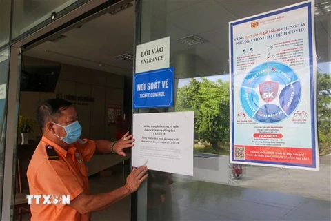 Nhân viên Bảo tàng Đà Nẵng dán các bảng tuyên truyền phòng dịch COVID-19 trước cửa ra vào. (Ảnh: Trần Lê Lâm/TTXVN)