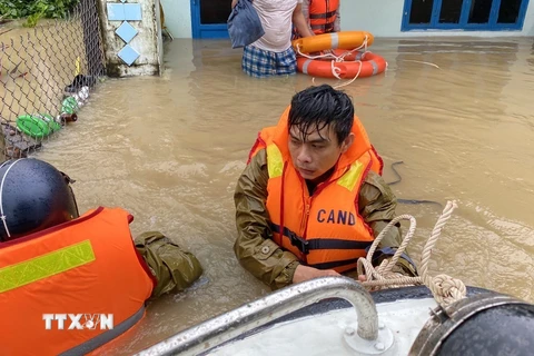 Công an huyện Tuy Phước dầm mình trong nước lũ hỗ trợ di chuyển người dân. (Ảnh: Tường Quân/TTXVN)