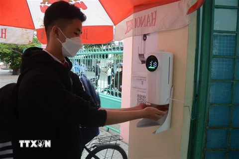 Học sinh đo thân nhiệt và rửa tay bằng nước sát khuẩn tại cổng trường. (Ảnh minh họa. Nguồn: TTXVN)