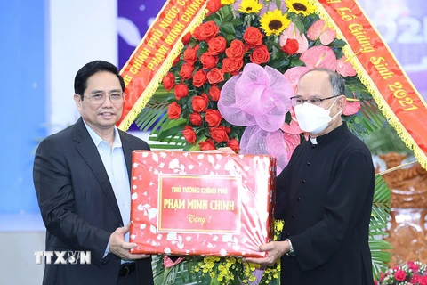 Thủ tướng Phạm Minh Chính tặng quà chúc mừng Giáng sinh giáo dân giáo xứ Long Hưng. (Ảnh: Dương Giang/TTXVN)