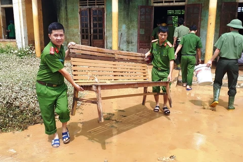 Các chiến sỹ công an huyện Hương Khê (Hà Tĩnh) chung tay dọn vệ sinh môi trường sau lũ tại xã Hương Đô. (Ảnh: Phan Quân/TTXVN)
