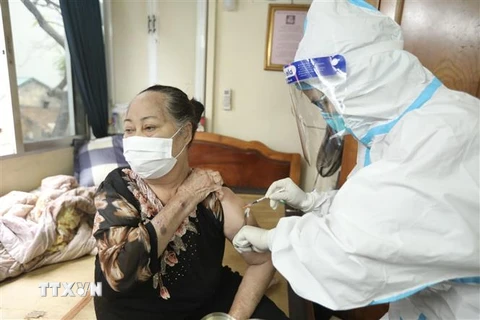 Nhân viên y tế phường Cửa Đông (quận Hoàn Kiếm, Hà Nội) tiêm cho người cao tuổi tại nhà. (Ảnh: Minh Quyết/TTXVN)
