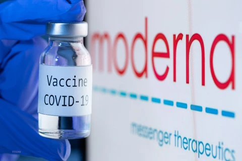 Vaccine ngừa COVID-19 bên cạnh biểu tượng của Công ty dược Moderna. (Ảnh: AFP/TTXVN)