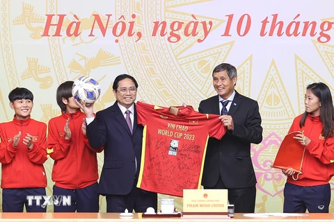 Huấn luyện viên Mai Đức Chung và các cầu thủ đội tuyển nữ Việt Nam tặng quà lưu niệm cho Thủ tướng Phạm Minh Chính. (Ảnh: Dương Giang/TTXVN)