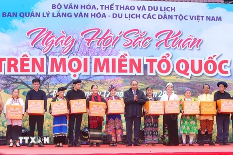 Chủ tịch nước Nguyễn Xuân Phúc tặng quà đồng bào dân tộc tại Làng Văn hóa-Du lịch các dân tộc Việt Nam. (Ảnh: Tuấn Đức/TTXVN)