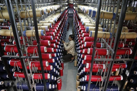 Công nhân kiểm tra các ống sợi trên máy dệt thảm tại một nhà máy ở ngoại ô Jammu, Ấn Độ. (Ảnh: AFP/TTXVN)