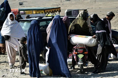 Người dân nhận thực phẩm cứu trợ của Hội Chữ thập Đỏ ở Kandahar, Afghanistan. (Ảnh: AFP/TTXVN)