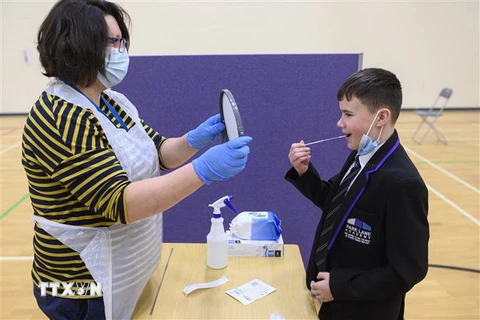 Nhân viên y tế hướng dẫn học sinh lấy mẫu xét nghiệm COVID-19 tại trường học ở Halifax, Tây Bắc vùng London, Anh. (Ảnh: AFP/TTXVN)