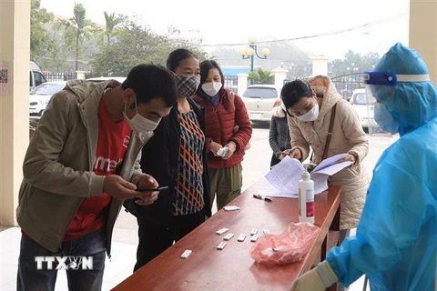 Người dân mang bộ kit đến xét nghiệm ở Trạm y tế lưu động số 1 xã Tân Triều, huyện Thanh Trì. (Ảnh: Hoàng Hiếu/TTXVN)