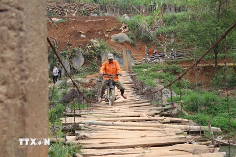 Người dân đi qua một cây cầu treo đã xuống cấp tại xã Chiềng Lương, huyện Mai Sơn. (Ảnh: Hữu Quyết/TTXVN)