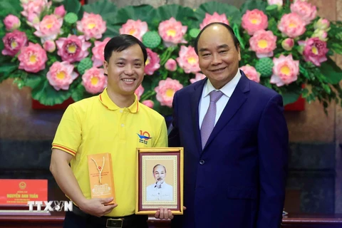 Chủ tịch nước Nguyễn Xuân Phúc tặng chân dung Chủ tịch Hồ Chí Minh cho đoàn viên thanh niên tiêu biểu. (Ảnh: Thống Nhất/TTXVN)