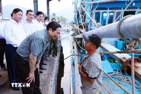Thủ tướng Phạm Minh Chính thăm hỏi, động viên ngư dân tàu cá đang neo đậu tại cảng cá xã Cà Ná. (Ảnh: Dương Giang/TTXVN)