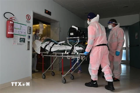 Nhân viên y tế chuyển bệnh nhân COVID-19 vào bệnh viện ở Cremona, Italy. (Ảnh: AFP/TTXVN)
