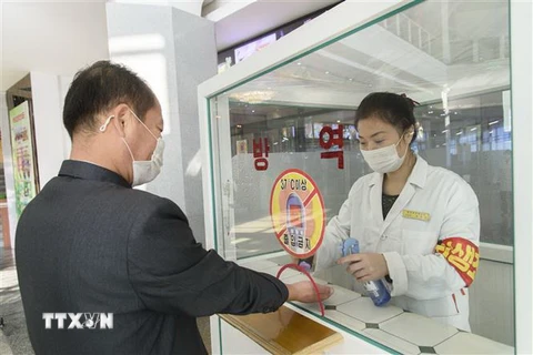 Khử khuẩn tay, đo thân nhiệt, nhằm ngăn chặn sự lây lan của dịch COVID-19 trước khi vào trung tâm thương mại ở Bình Nhưỡng, Triều Tiên. (Ảnh: AFP/TTXVN)