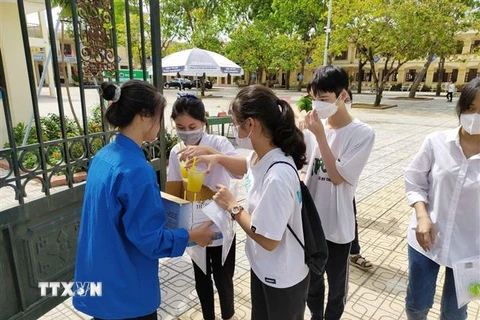  Thanh niên tình nguyện xã Minh Tân cung cấp nước mía miễn phí cho thí sinh và người nhà thí sinh. (Ảnh: TTXVN phát)