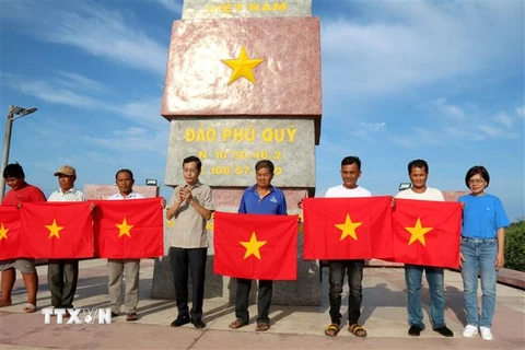 Đại diện lãnh đạo Cơ quan TTXVN khu vực phía Nam và lãnh đạo Công ty trách nhiệm hữu hạn một thành viên ITAXA tặng cờ Tổ quốc cho ngư dân tại Phú Quý. (Ảnh: Nguyễn Thanh/TTXVN)