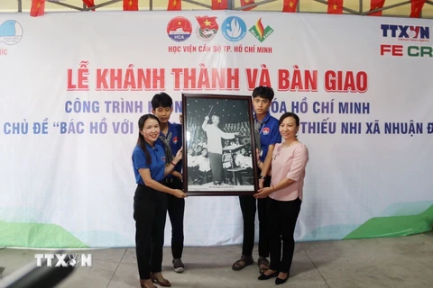 Đại diện Cơ quan thường trú TTXVN tại Thành phố Hồ Chí Minh tặng bức ảnh Chủ tịch Hồ Chí Minh cho Ủy ban Nhân dân xã Nhuận Đức. (Ảnh: Thu Hương/TTXVN)